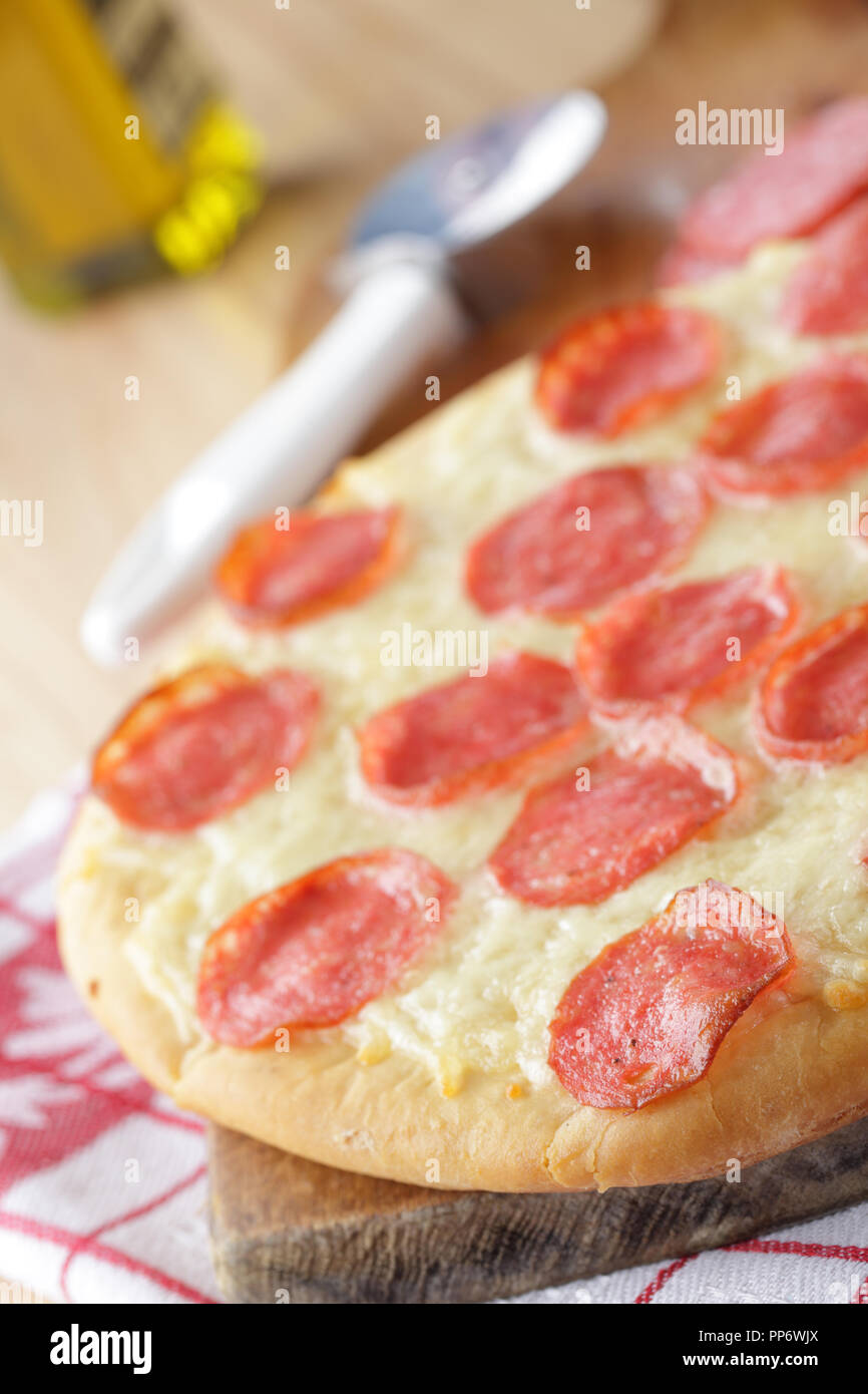 Avec la pizza au Pepperoni salami et fromage sur la planche à découper en bois Banque D'Images