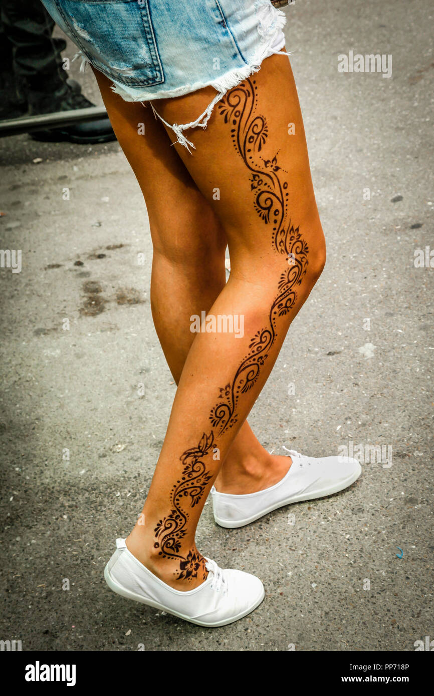 Jeunes trendy woman wearing white formateurs et denim Short cut-off a un tatouage depuis le haut de sa cuisse à ses chevilles marchant dans la rue Banque D'Images