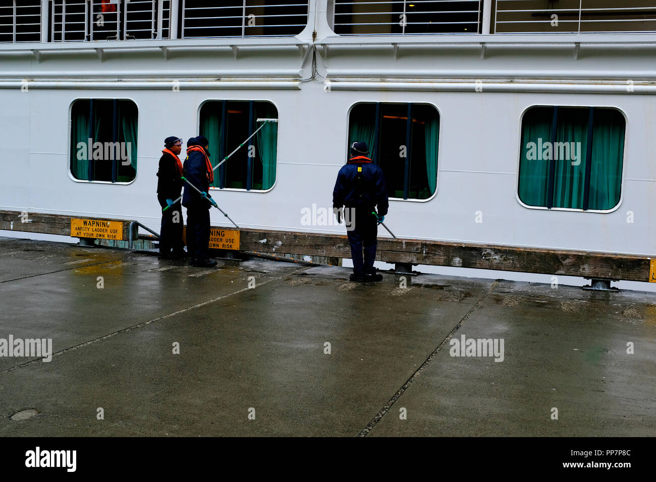 Le personnel de la ligne de croisière peinture du navire alors qu'il est dans le port Banque D'Images