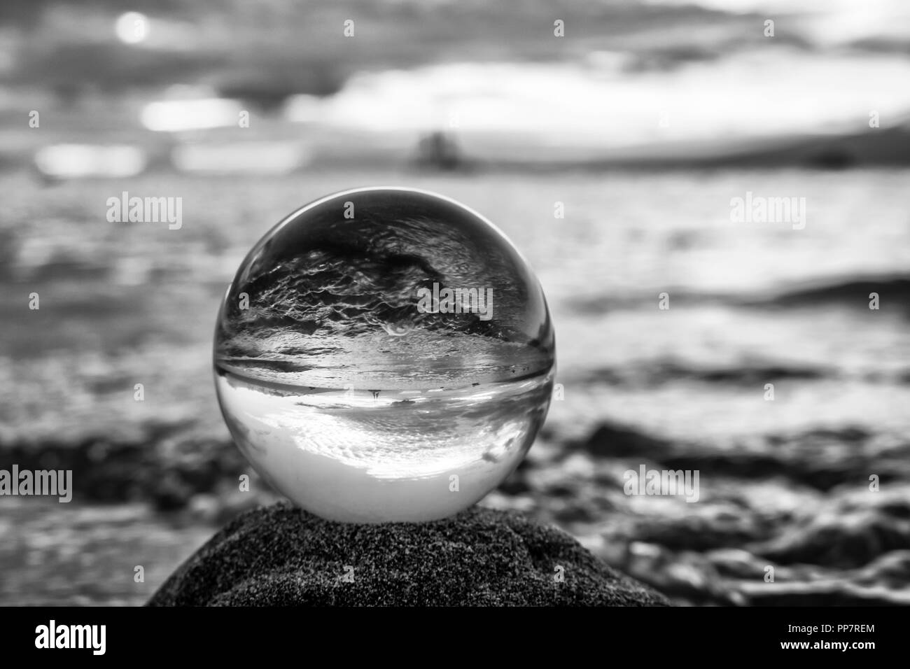 Paysage marin de l'océan avec des vagues capturés en réflexion dans la bille de verre en noir et blanc Banque D'Images