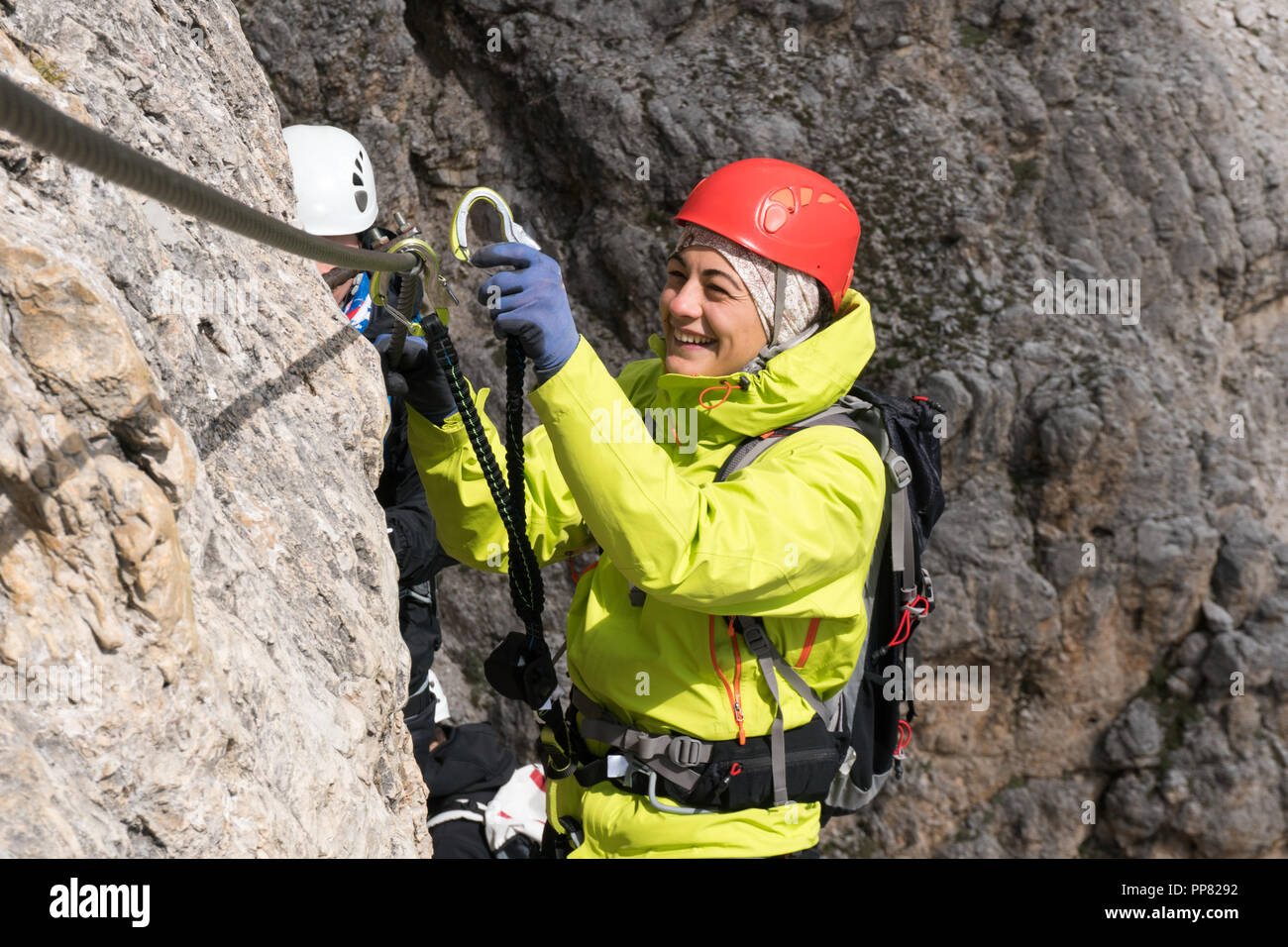 Jeune femme d'alpiniste sur une via ferrata dans les Dolomites en Alta Badia en cliquant sur mousquetons dans le câble Banque D'Images