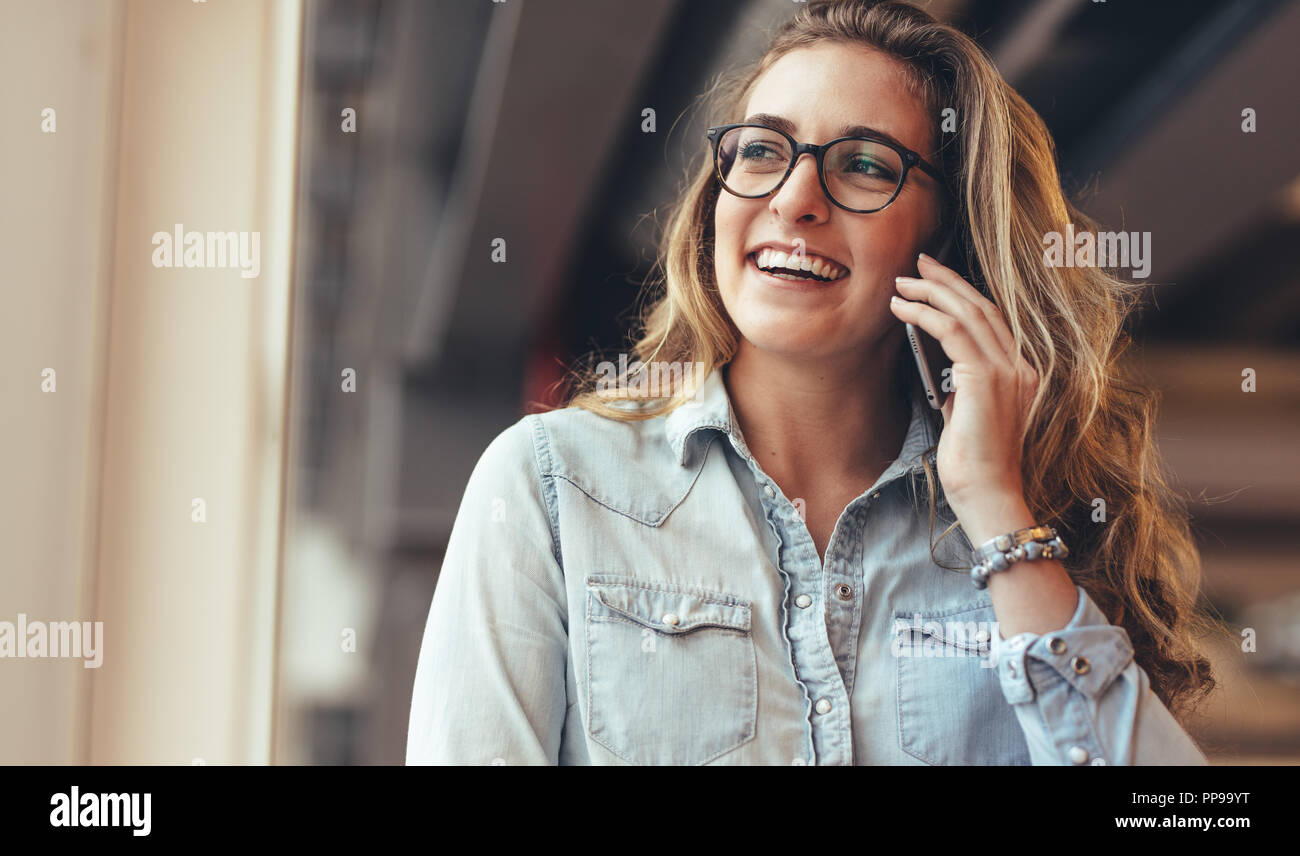 Smiling businesswoman talking on mobile phone in office. Cheerful woman entrepreneur sur un appel téléphonique dans le bureau. Banque D'Images