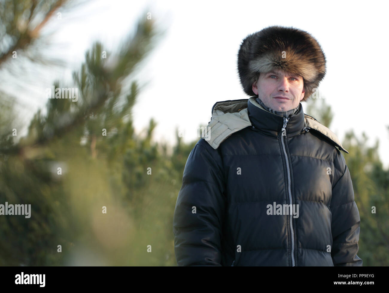 Homme russe en vêtements d'hiver et chapeau de fourrure russe une forêt de  pins Photo Stock - Alamy