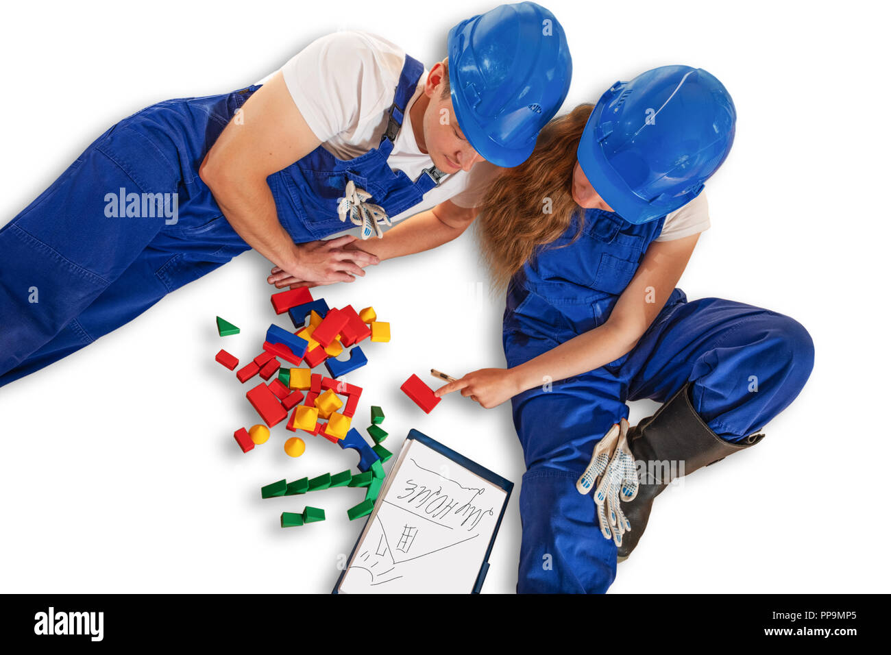Un jeune couple envisage de construire une maison. Jeune couple avec bébé cubes jouant dans la construction d'une maison. Les gens dans des combinaisons jouer les jouets pour enfants dans la construction d'un Banque D'Images