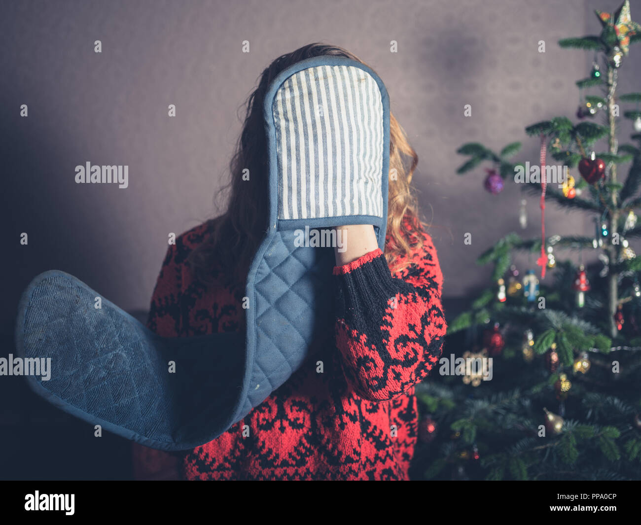 Une jeune femme avec des gants est debout par l'arbre de Noël Banque D'Images