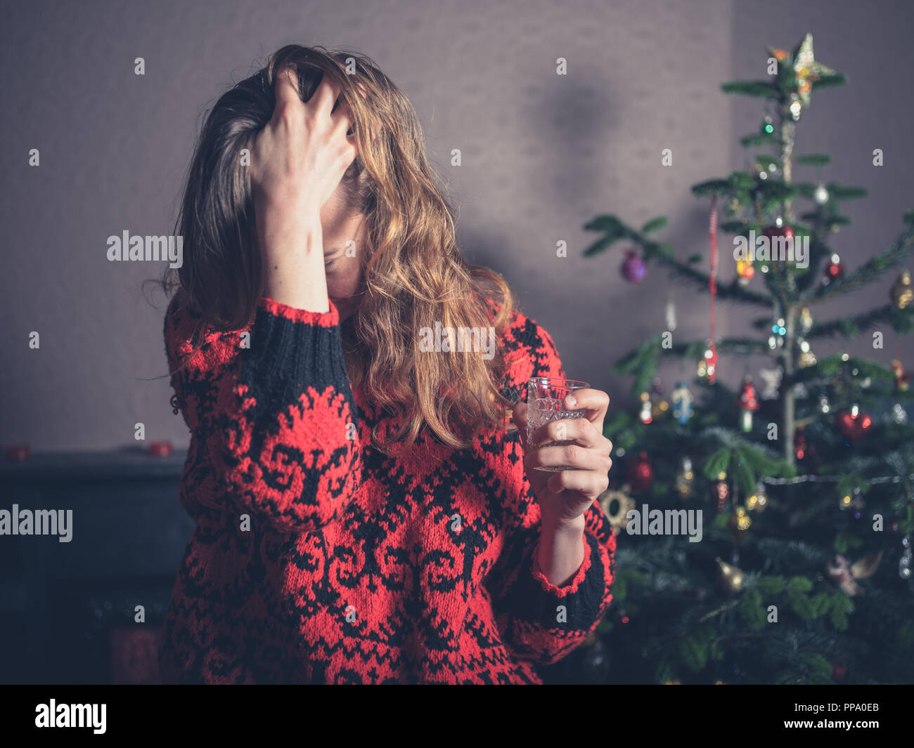 Une jeune femme se tient debout a souligné par un arbre de Noël Banque D'Images