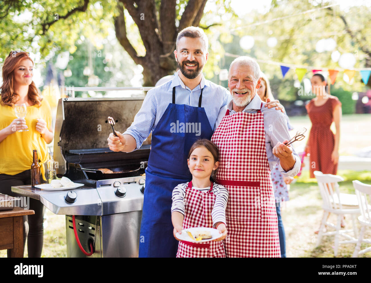 Un homme mûr avec famille et amis à la cuisson des aliments sur un barbecue. Banque D'Images