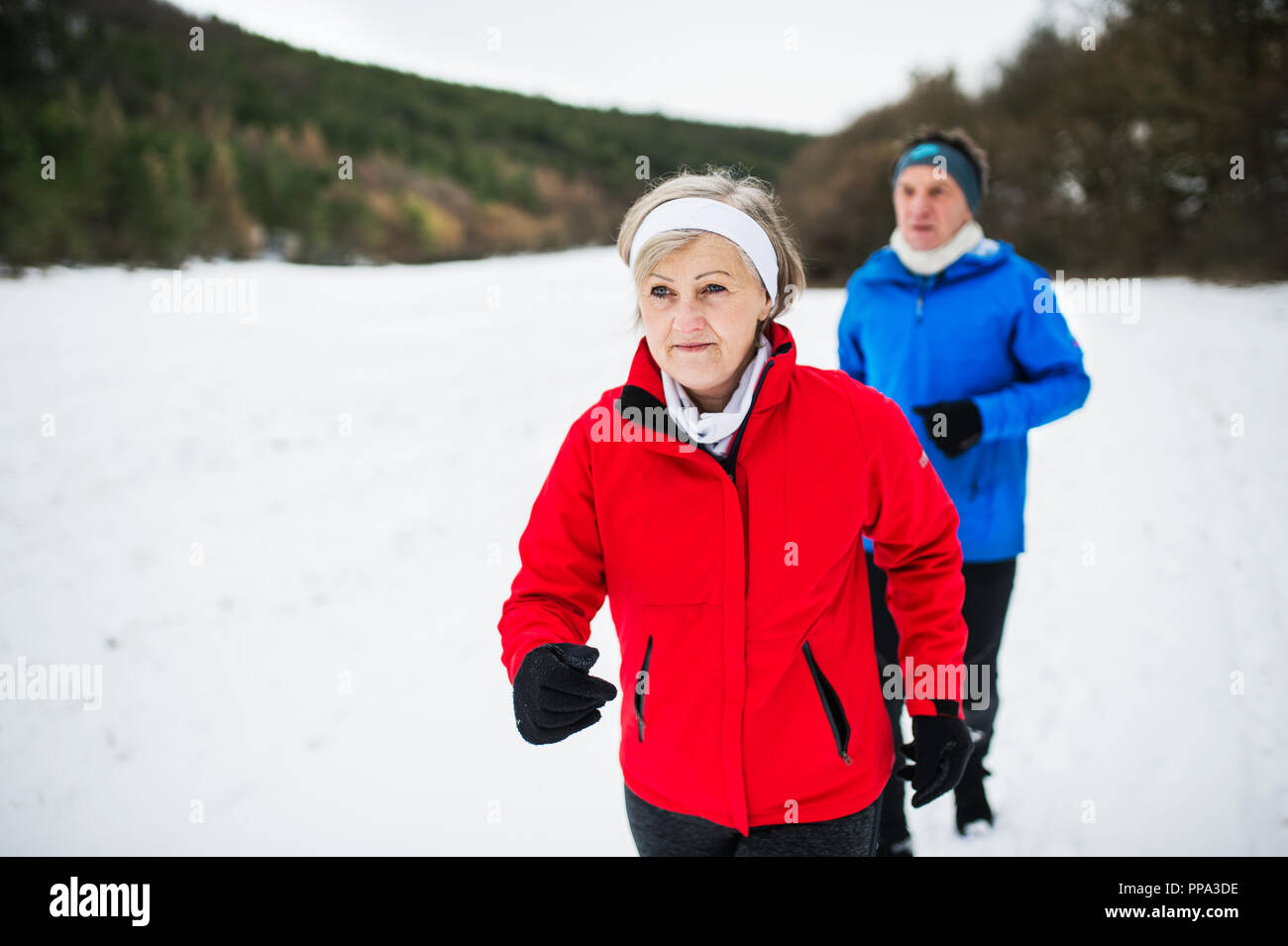 Une vue de face du couple jogging en hiver neige la nature. Banque D'Images