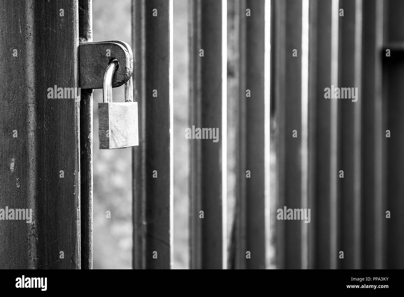 La porte fermée avec barres verticales avec cadenas fermé en noir et blanc Banque D'Images
