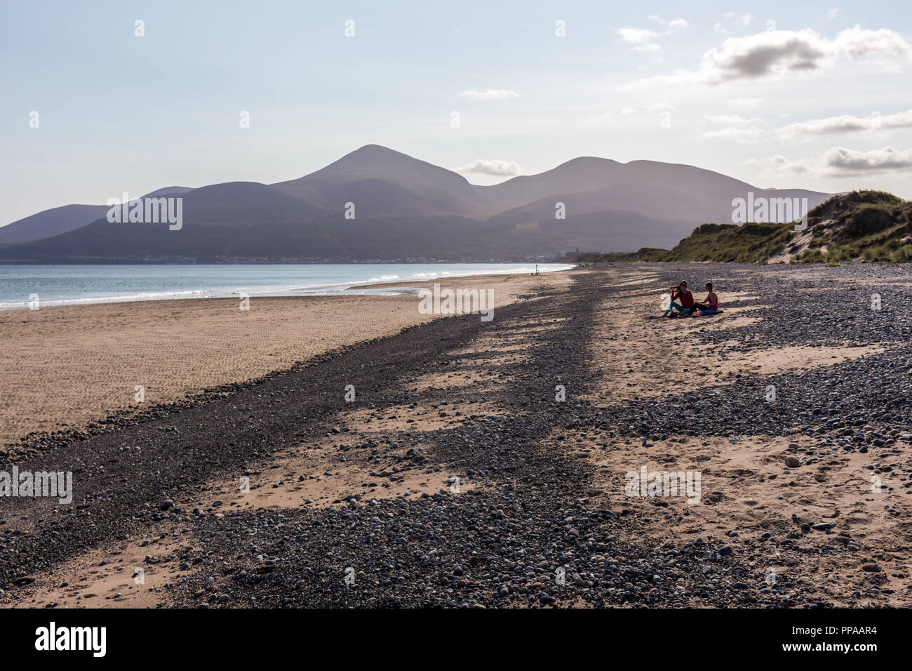 Des gens assis de détente sur une plage tranquille avec vues sur les montagnes de Mourne. Murlough beach, Newcastle, comté de Down, Irlande du Nord. Banque D'Images