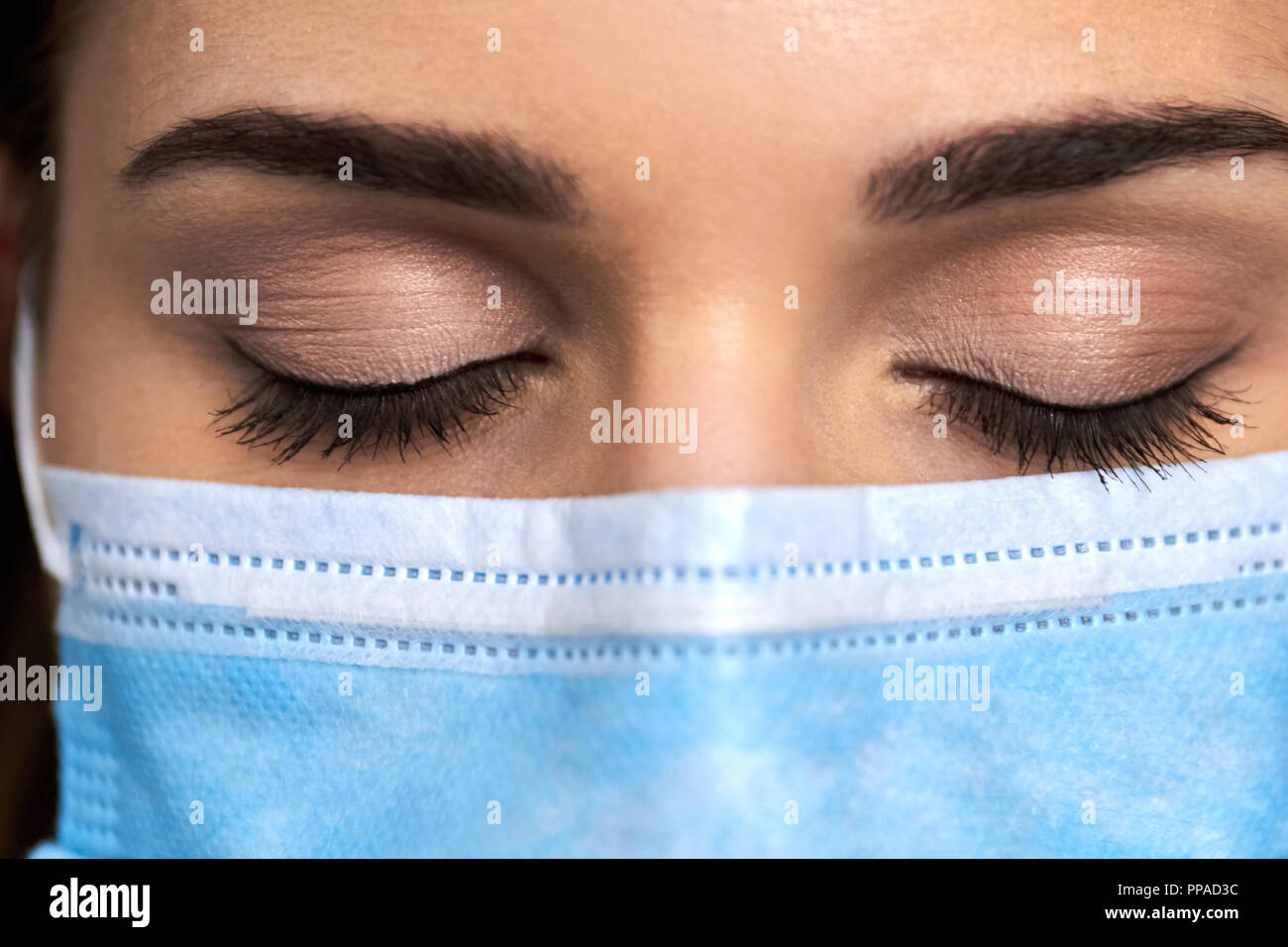 Femme médecin en masque aux yeux clos. L'affichage macro visage féminin en masque de protection médicale. Méditation avant l'opération. Banque D'Images