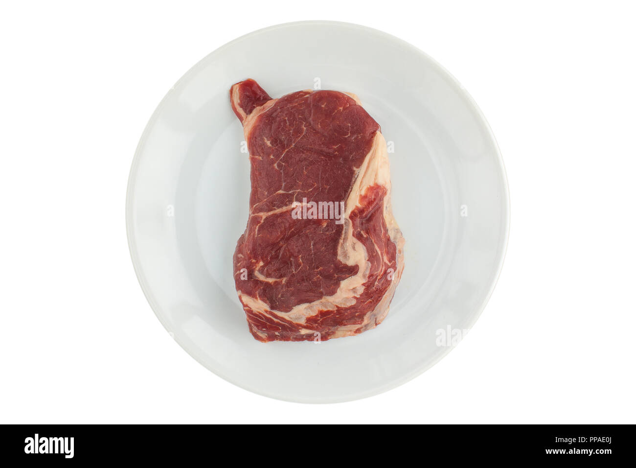 Un morceau de viande crue (ripe) steak sur une plaque blanche sur un fond isolé Banque D'Images