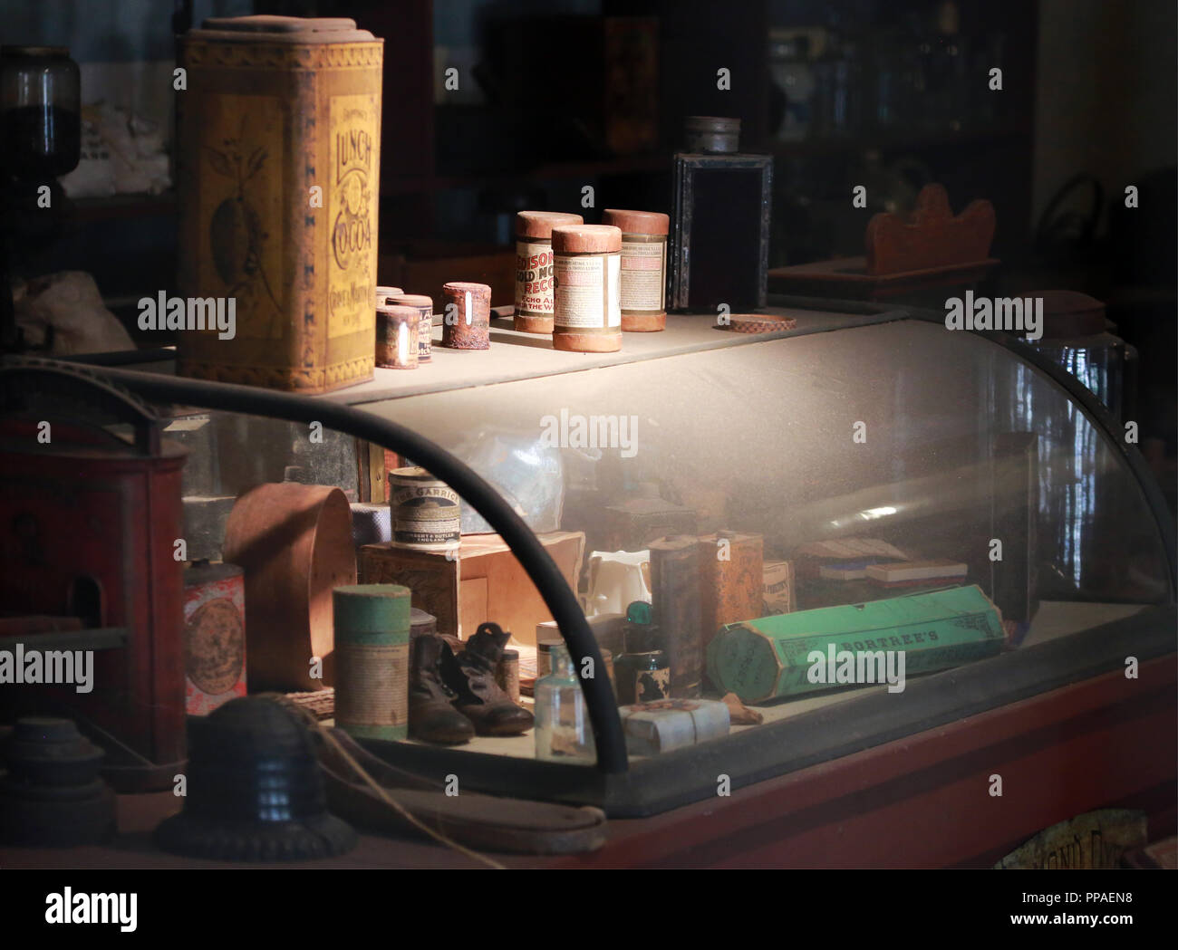 Vitrine de verre courbé sur le comptoir du magasin de pays avec des artefacts dans la lumière contrastée Banque D'Images