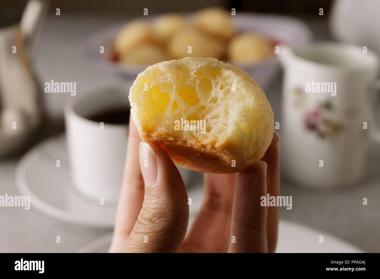 Close-up of a mordu brésilien maison pain au fromage (également connu sous le nom de Pão de Queijo) ; table de petit déjeuner dans l'arrière-plan. Focus sélectif. Banque D'Images