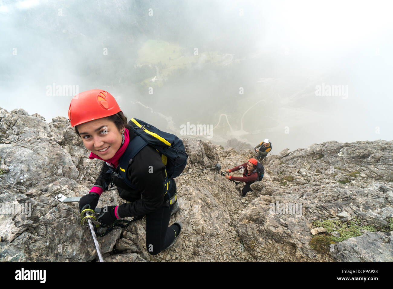 Trois jeunes attractive male et femelle d'alpinistes sur une pente raide et exposé Via Ferrata en Alta Badia dans le Tyrol du Sud dans les Dolomites italiennes Banque D'Images