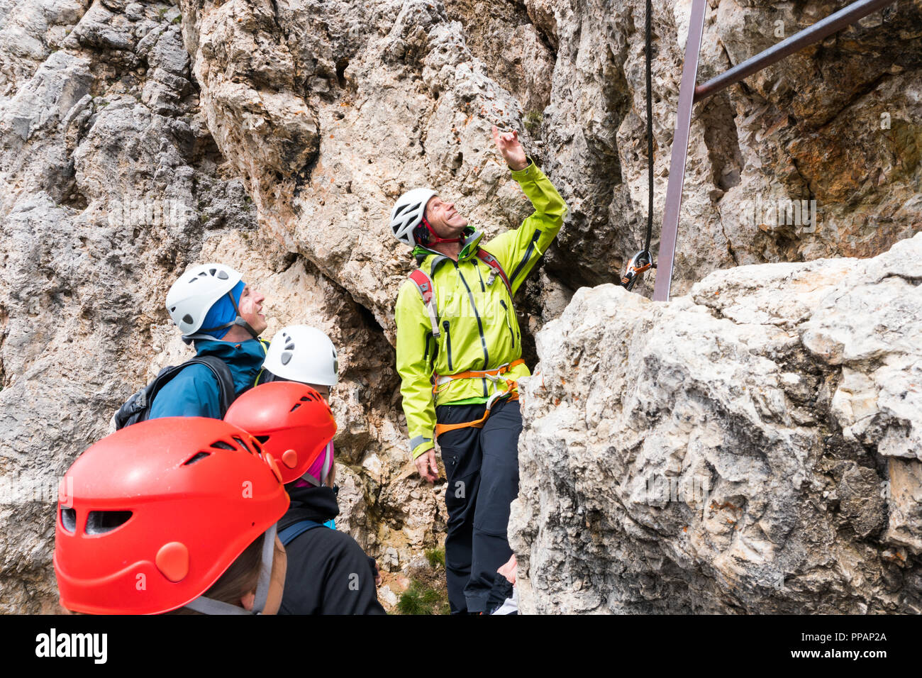 Un guide de montagne mâle indique à de jeunes grimpeurs au début d'une via ferrata dans les Dolomites en Italie du nord en Alta Badia Banque D'Images