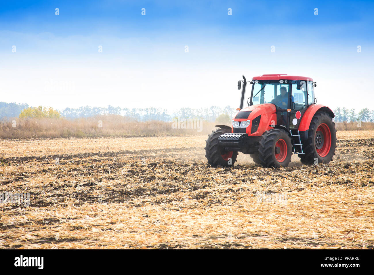 Tracteur rouge moderne travaillant sur le terrain à l'automne 24 Banque D'Images