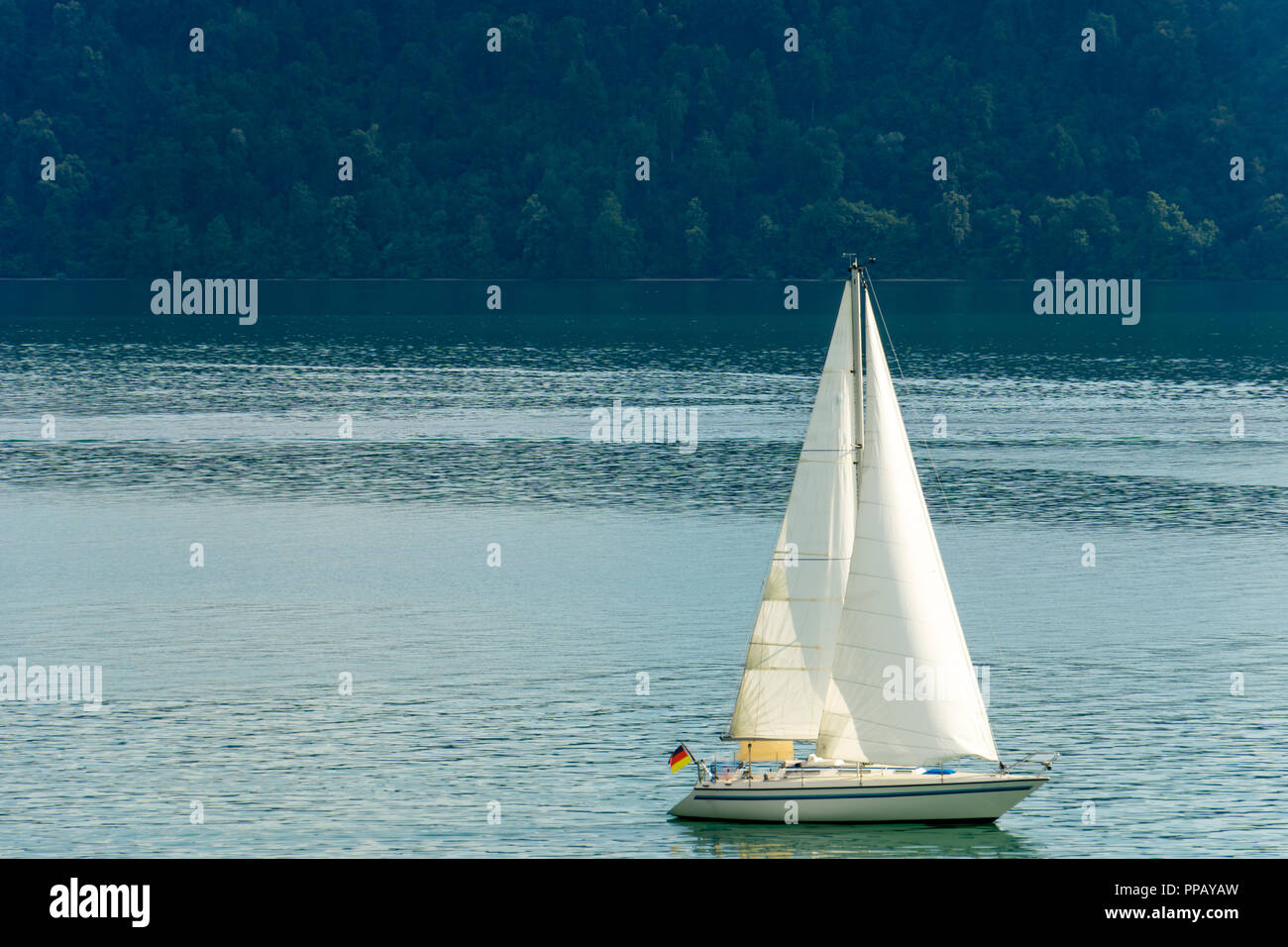 Bateau à voile avec voiles blanches sur l'eau silencieuse Banque D'Images