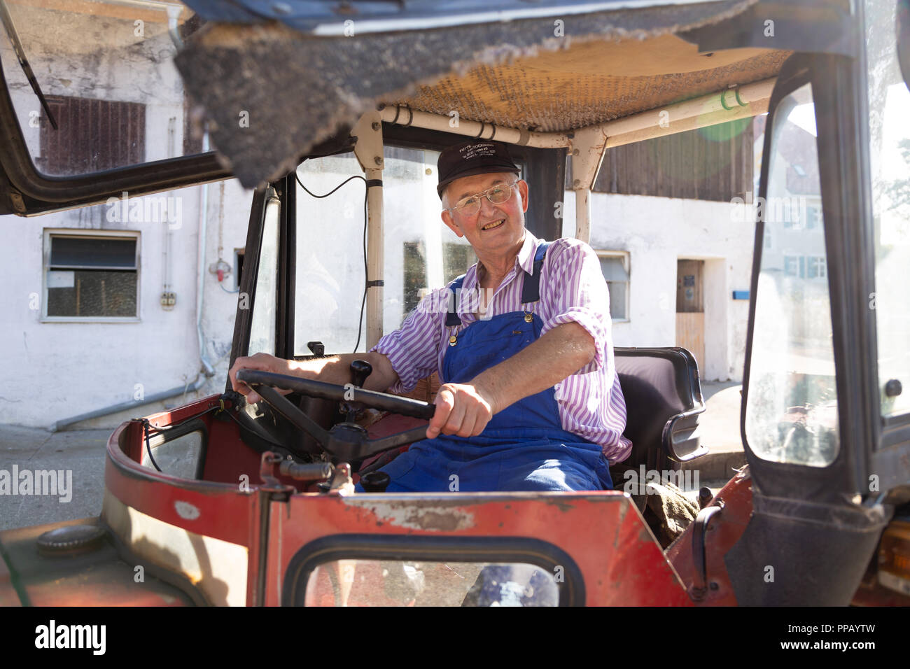 Agriculteur âgé assis dans son tracteur dans une ferme dans les régions rurales de Bavière, Allemagne Banque D'Images