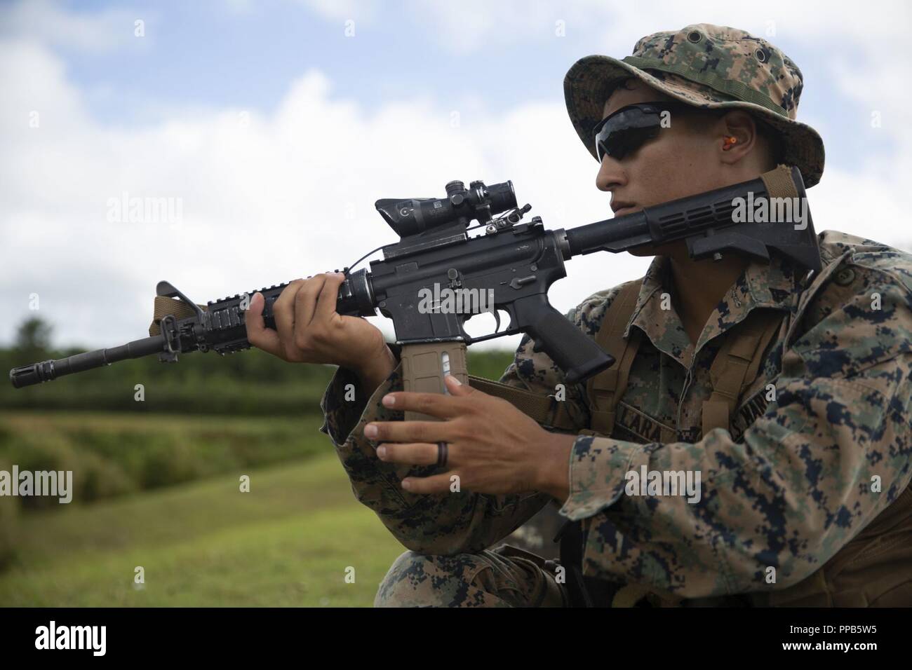 Le Cpl. Justin Lara ajuste son écharpe pendant sa période de décharge tout en assistant à un cours d'entraîneurs de l'adresse au tir de combat au Camp Hansen, Okinawa, Japon, 14 août 2018. Lara, originaire d'Austin, Texas, et d'un fantassin du 2e Bataillon, 3e Régiment de Marines. "Sur la plage que vous avez besoin de confiance - confiance pour aller jusqu'au bout, la confiance en vous-même, et la confiance dans vos tirs," dit-il. Lara a dit qu'il aspire à enseigner l'adresse au tir pour aider ses collègues de Marines améliorer et est excité à l'occasion le cours MCC lui a donné. Banque D'Images