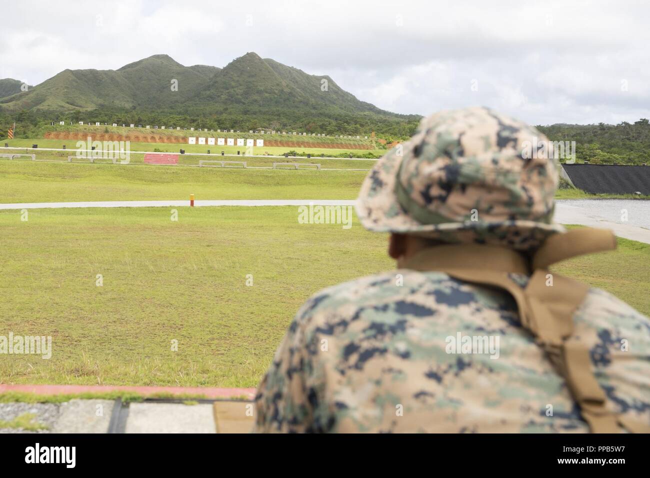 Le Cpl. Justin Lara attend que son fusil d'être effacés à la fin de l'allumage sur le champ de tir de l'adresse au tir de combat au cours d'un cours d'entraîneurs au Camp Hansen, Okinawa, Japon, 14 août 2018. Lara, originaire d'Austin, Texas, et d'un fantassin du 2e Bataillon, 3e Régiment de Marines. "J'ai tourné quatre fois d'experts, cette fois va être la cinquième," dit-il. Lara a dit qu'il a hâte d'être sur le fusil et se déplacer pour le prochain défi dans le cours. Le cours couvre également la prise de distance inconnue, nuit, et champ de tir. Banque D'Images