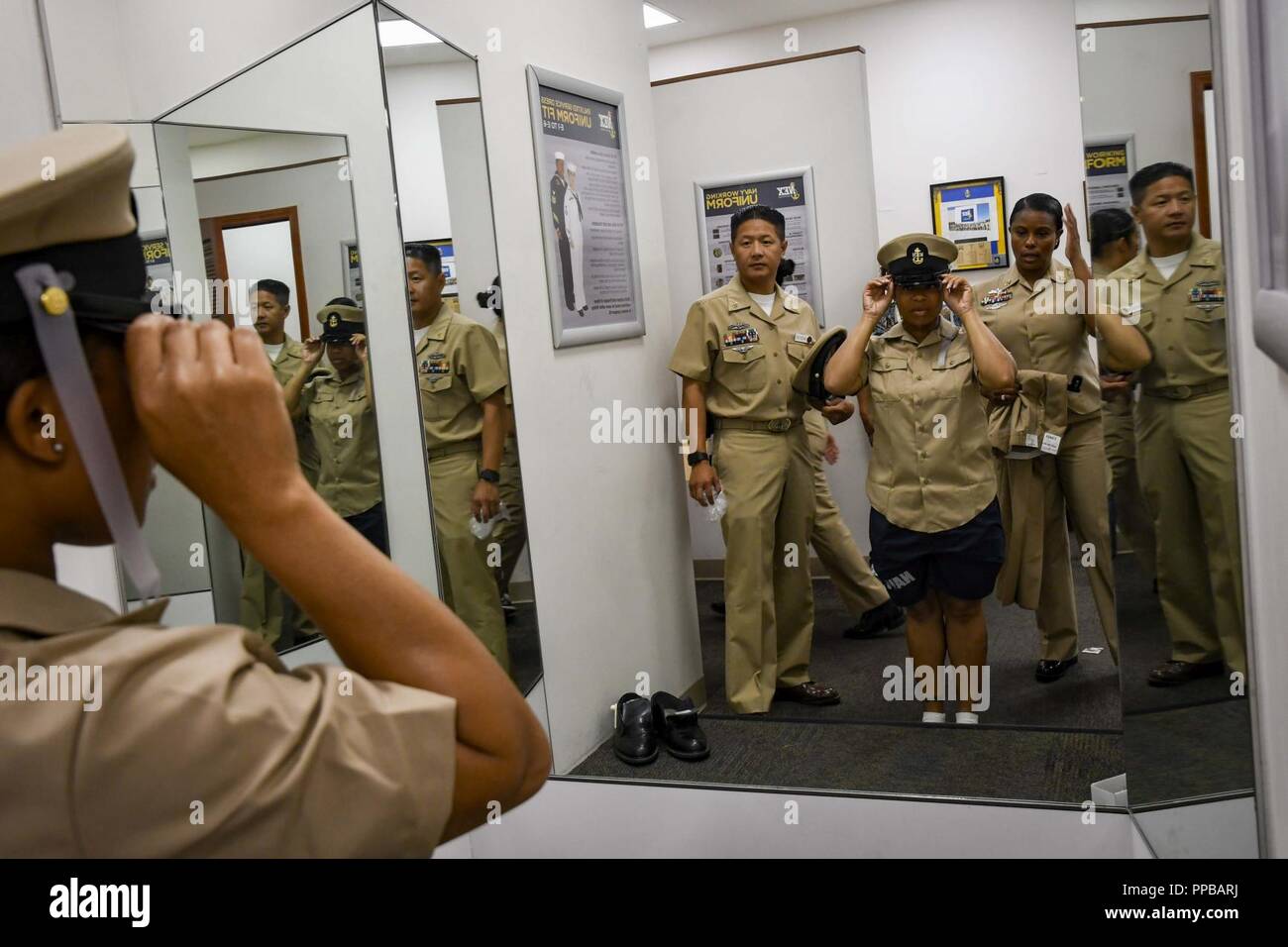 SAN DIEGO (Août 17, 2018) Le Magbitang Hôpital Corpsman Ronnie, gauche, attribué à Naval Medical Center San Diego, et les cadres supérieurs de l'hôpital principal de cristal Corpsman Ingram, affecté au 1er Bataillon de soins dentaires, d'enseigner en 1ère classe Ordnanceman Aviation Dominique Cantine comment porter sa couverture lors d'un raccord en uniforme. Bien que Canteen a été sélectionné pour le premier maître de elle ne sera pas capable de porter jusqu'à son nouveau grade promu lors d'une cérémonie le mois prochain. Banque D'Images