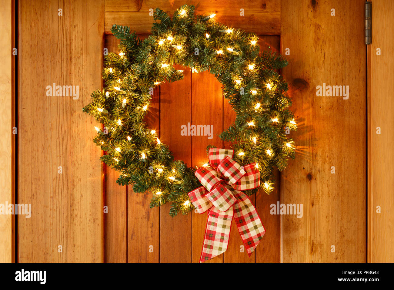 De belles décorations de Noël wreath with ribbon bow et lumières sur fond de porte avant en bois. Simple, style rustique maison de décor à la maison. Banque D'Images