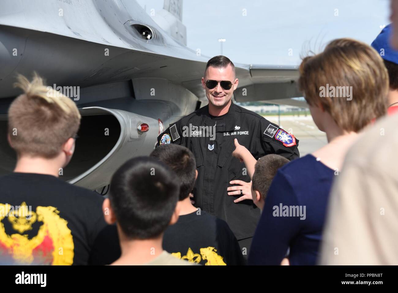 U.S. Air Force Tech. Le Sgt. Dominic Dizes, F-16 Viper de l'équipe Chef d'équipe dédiée, sourit comme un enfant lui pose une question au cours d'une visite d'un F-16 Fighting Falcon sur la ligne de vol à Cleveland Hopkins International Airport à Cleveland, Ohio, 30 août 2018. Dizes a parlé à un groupe de jeunes sur les capacités du F-16 Fighting Falcon et ce qu'il fait pour maintenir son avion. Banque D'Images