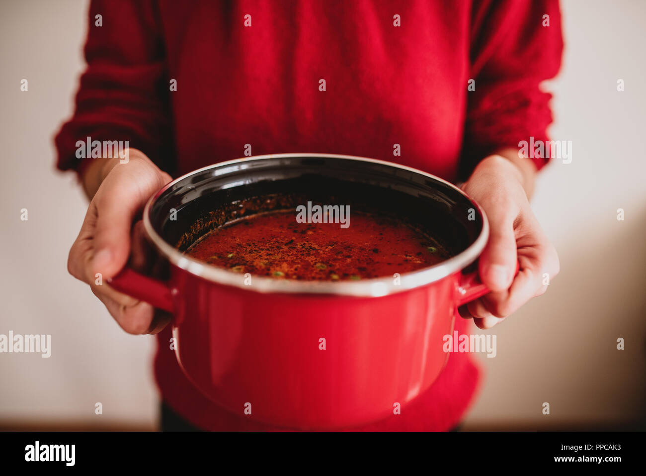 Les mains tenant pot rouge avec soupe aux légumes. Concept d'aliments sains Banque D'Images