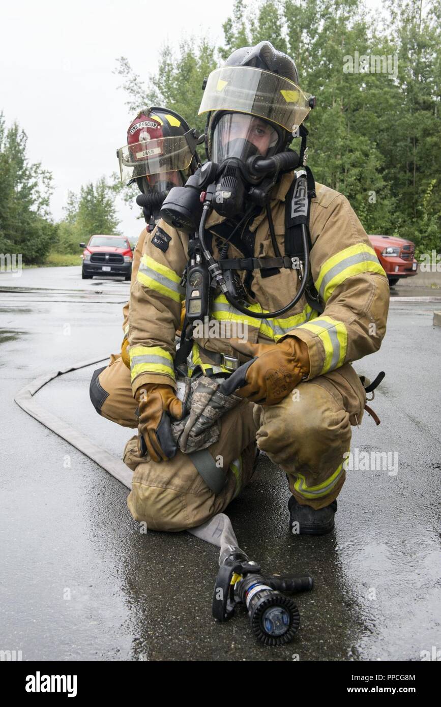 U.S. Air Force Protection incendie spécialistes chargés de la 673e Escadron d'Ingénieur Civil, se préparent à entrer dans une structure simulée en temps de guerre l'incendie Incendie formation à l'état de préparation de base commun Elmendorf-Richardson, Alaska, le 23 août, 2018. Au cours de la formation de préparation à l'Armée de l'air les pompiers ont enfilé divers niveaux de protection axé sur la mission de posture (MOPP) et pratiqué répondant aux situations d'urgence à une simulation d'environnement toxique lors d'un incident chimique, biologique, radiologique ou nucléaire grève. Banque D'Images