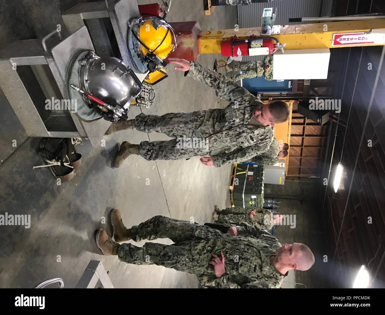 La Marine américaine de première classe constructeur Justin Lieder, attribué à l'équipe de construction sous-marine 2 (2) de l'UCT, explique les capacités et les limites d'un casque de plongée utilisés par UCT 2 à 30e Régiment de la construction navale, le capitaine Commodore Steven Stasick, lors d'une tournée d'UCT 2 situé à Port Hueneme, Californie, le 24 août 2018. La force de la construction navale (NCF) offre adaptée à la tâche, adaptables et efficaces au combat des forces d'ingénierie et de construction qui se déploient à l'appui des objectifs de la Marine à l'échelle mondiale et permettre à la logistique pour les opérations de la flotte répartie. UCT 2 est un élément clé Banque D'Images