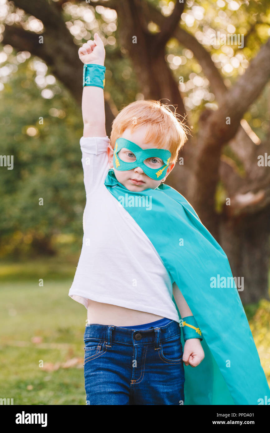 Cute adorable preschool caucasien enfant jouant en costume de super-héros. Kid garçon portant masque et le cap vert s'amuser en plein air dans le parc. Happy active ch Banque D'Images