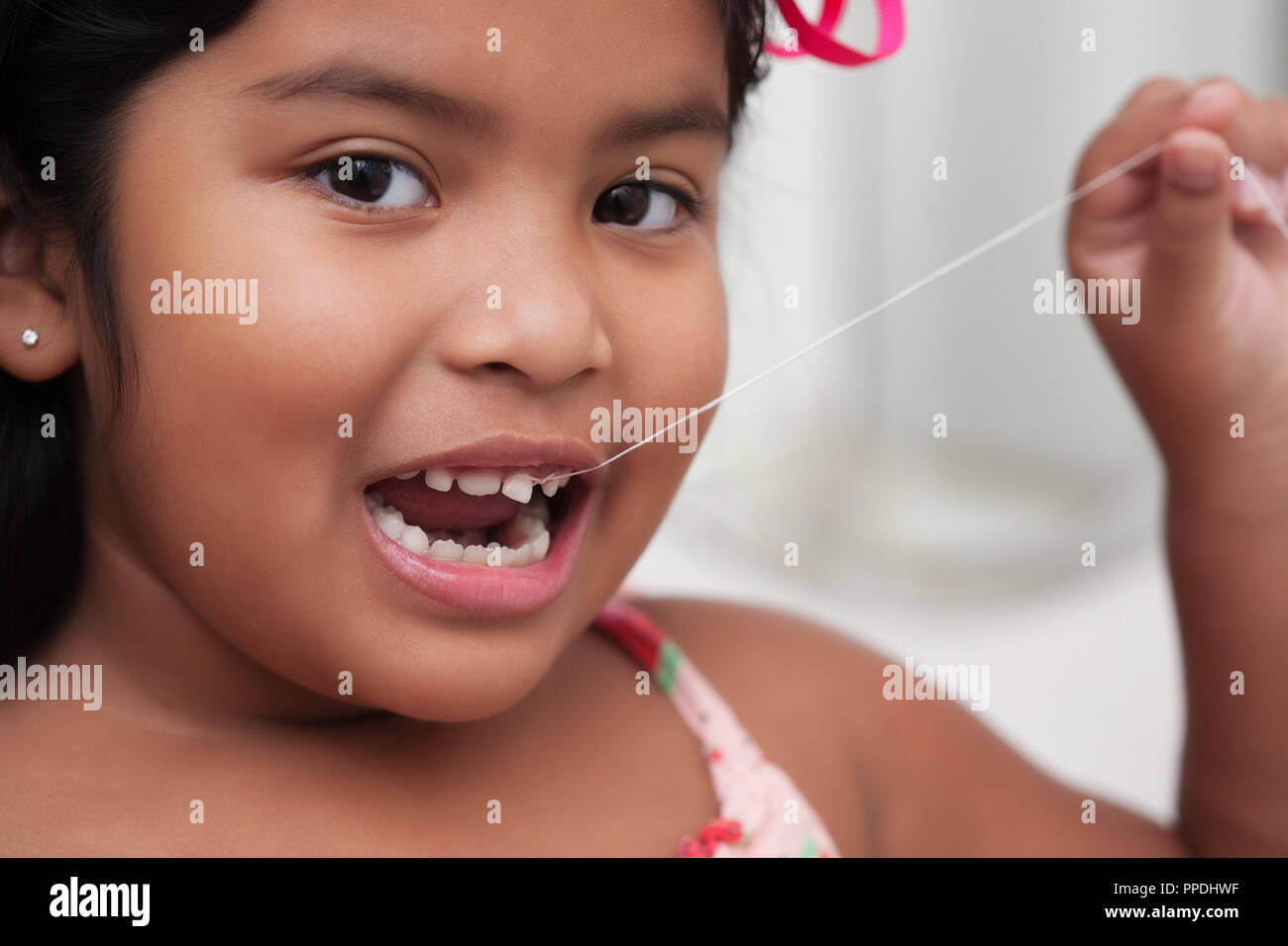 Jeune fille heureuse de sortir son bébé dent avec une ficelle attachée à la dent lâche Banque D'Images