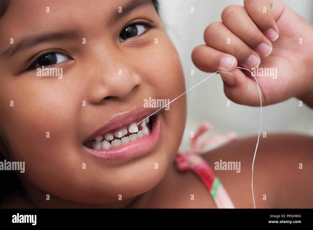 Cute girl tirant ses dents desserrés à l'aide d'une chaîne tout en la tenant fermement avec sa main Banque D'Images
