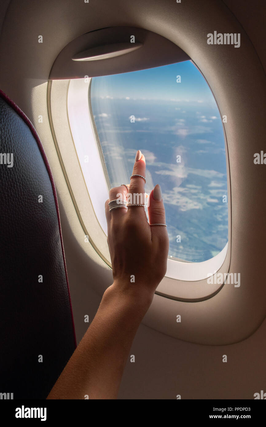 Femme à la fenêtre à travers de l'avion pendant le lever du soleil. Banque D'Images