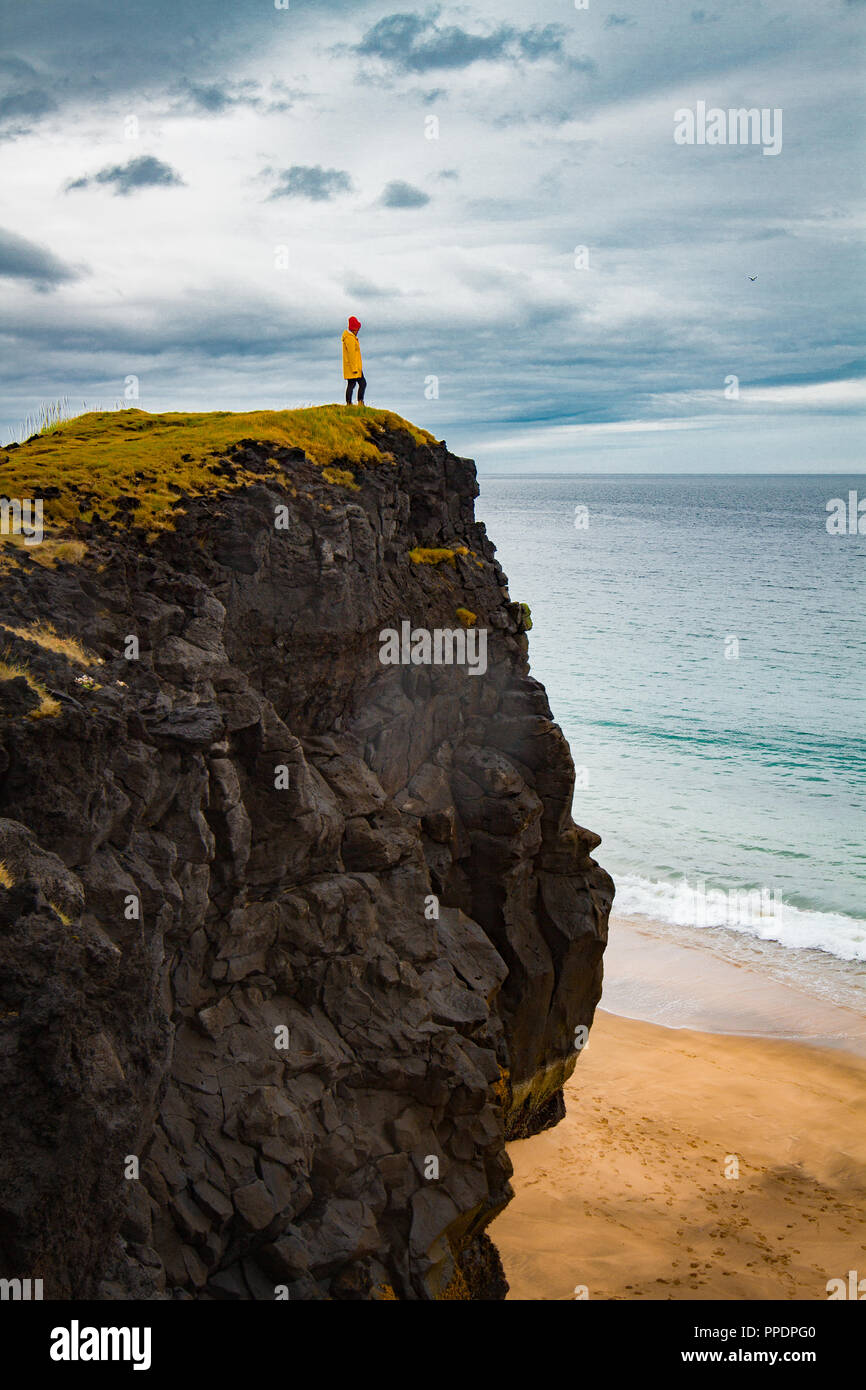 Paysage islandais, personne en imperméable jaune. Amasing rock, l'Islande. Banque D'Images