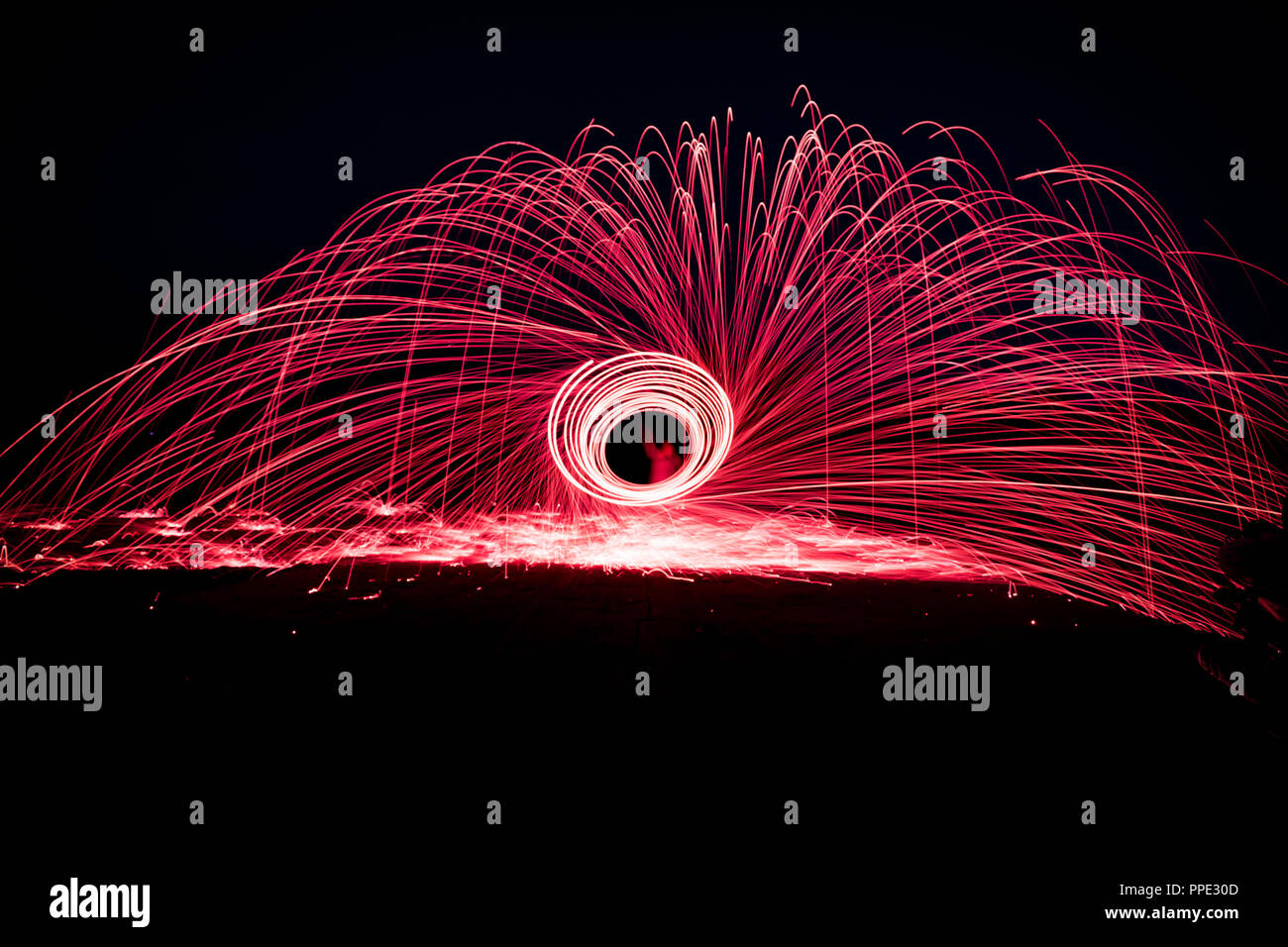 Peinture de lumière avec la filature de la laine d'acier, créant de magnifiques traînées circulaire de lumière pourpre de la combustion de la laine d'acier à l'intérieur d'un fouet attaché à une corde. Banque D'Images