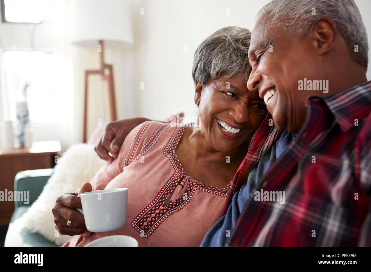 Senior Couple Sitting on Sofa At Home de vous détendre avec une boisson chaude Banque D'Images