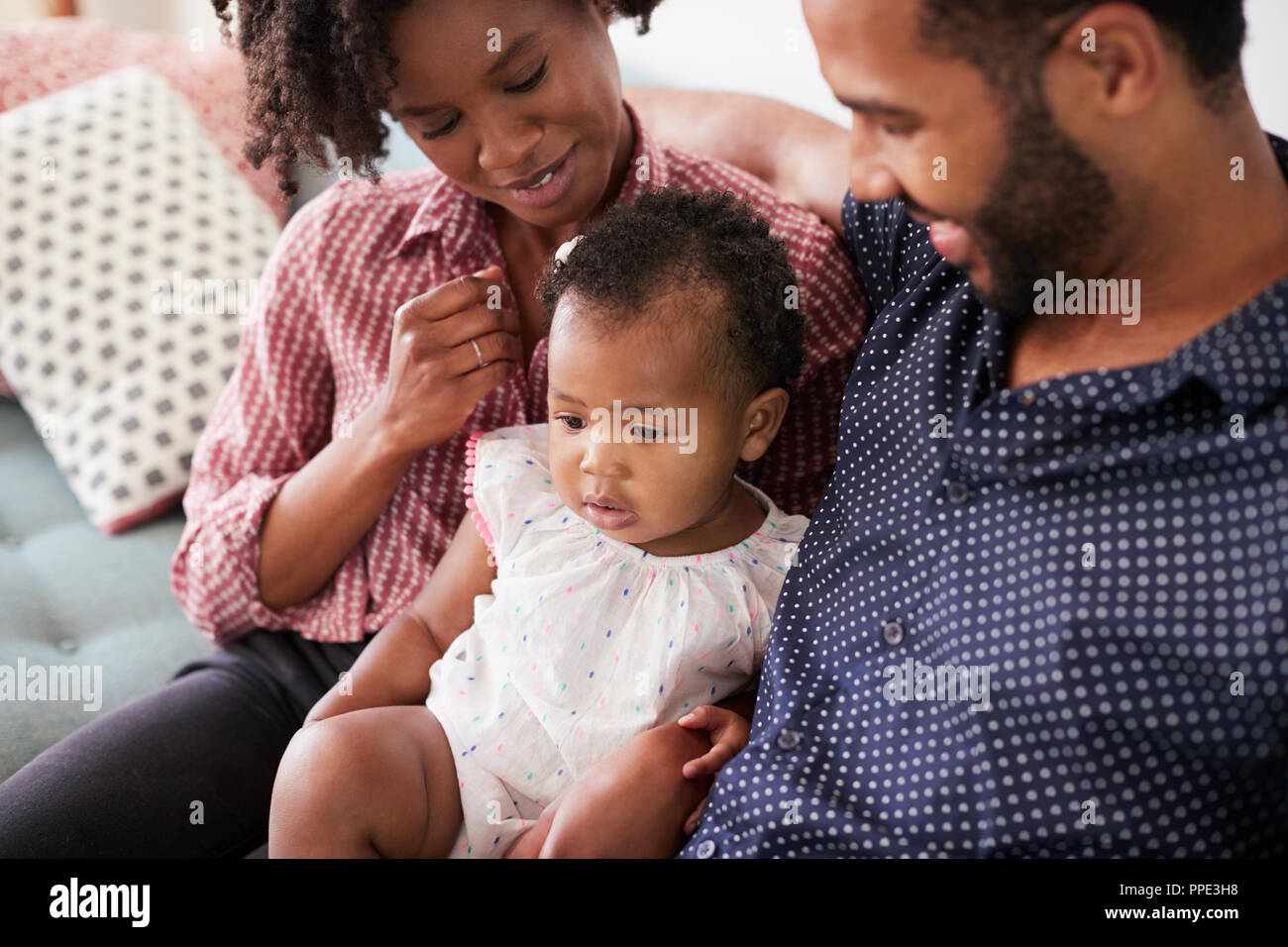 Famille avec Baby Daughter Sitting on Sofa At Home Together Banque D'Images