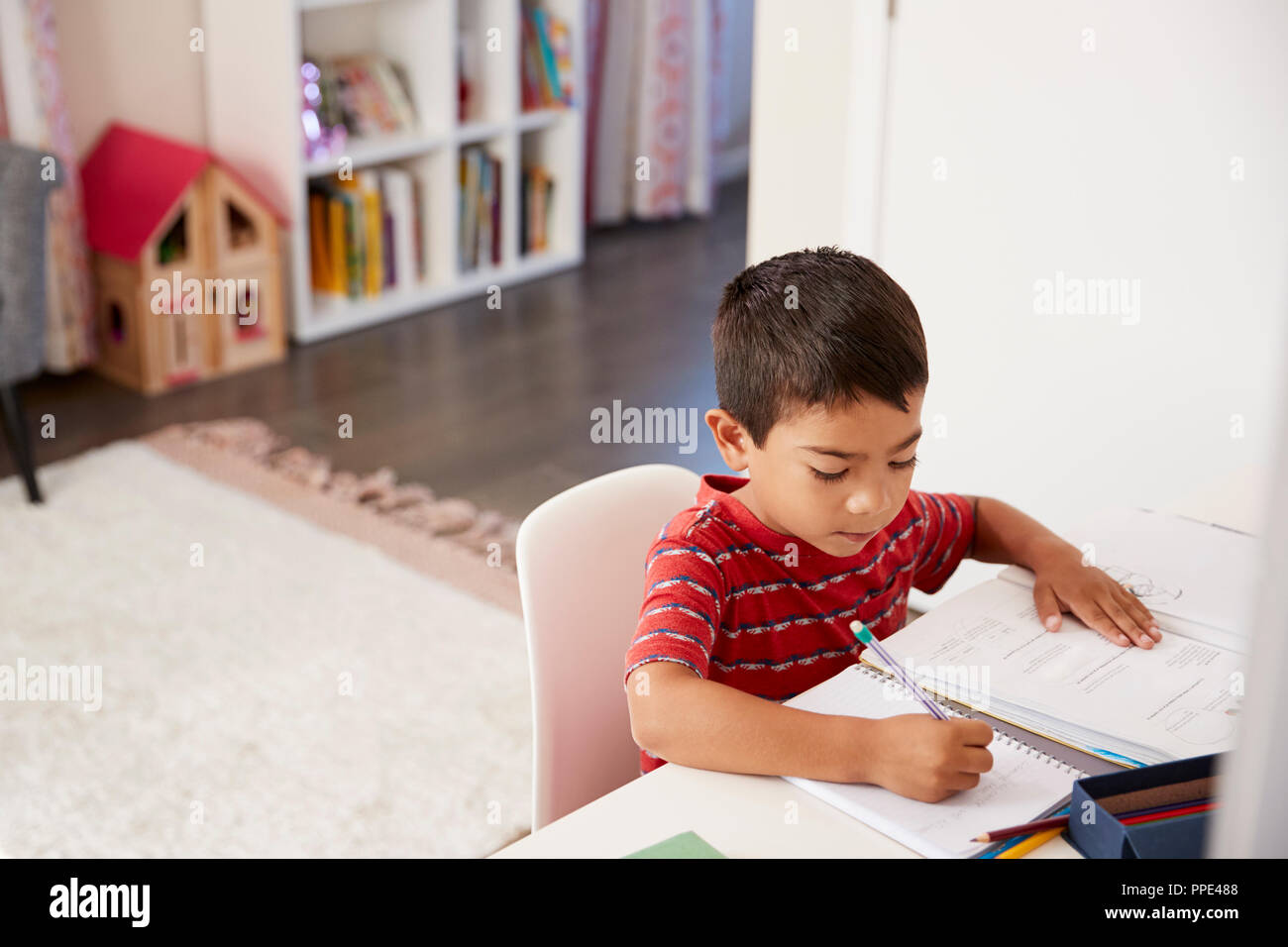 Jeune garçon assis au bureau dans la Chambre à faire leurs devoirs Banque D'Images