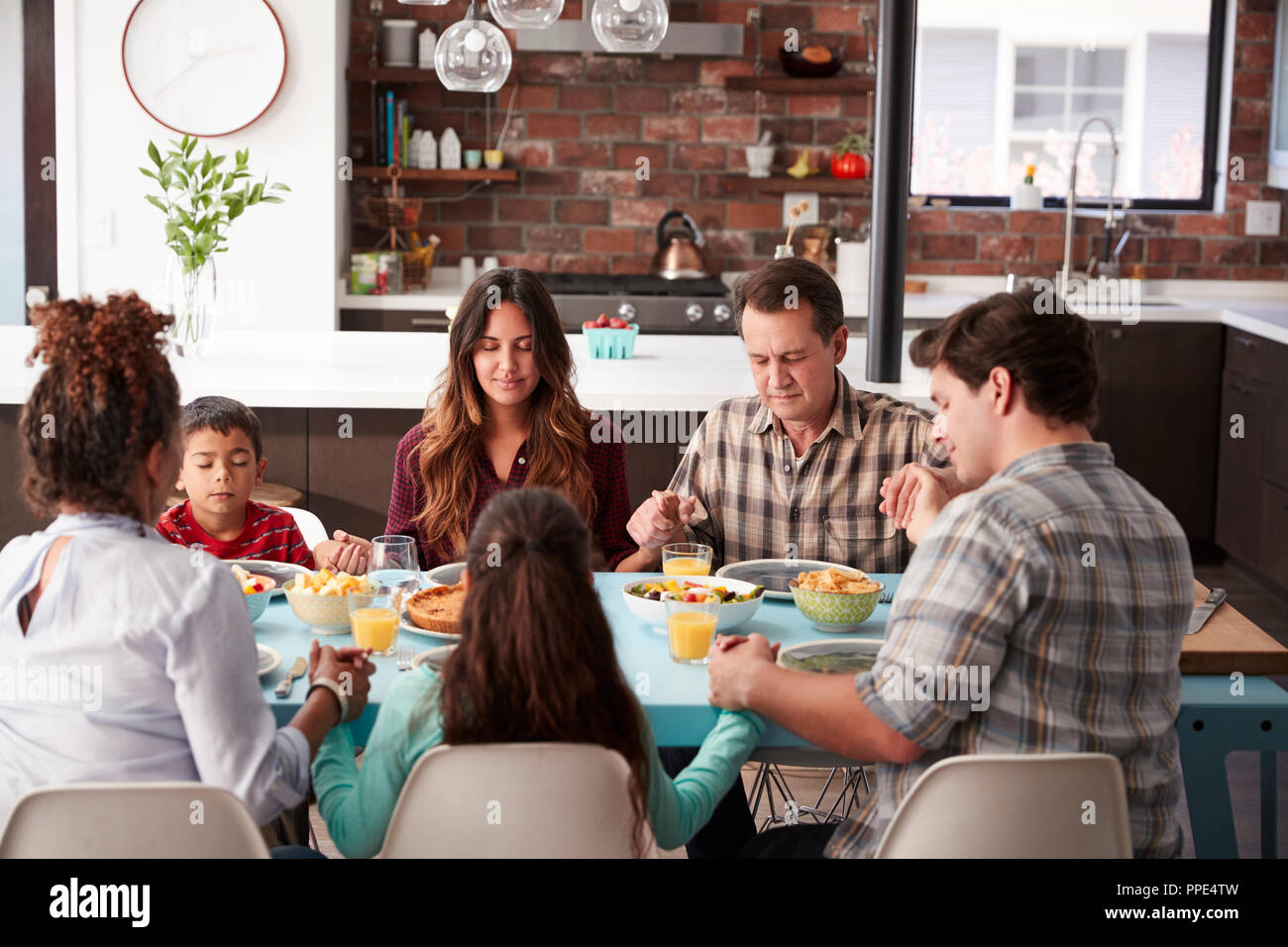 Multi Generation Family priant Avant repas autour de la table à la maison Banque D'Images
