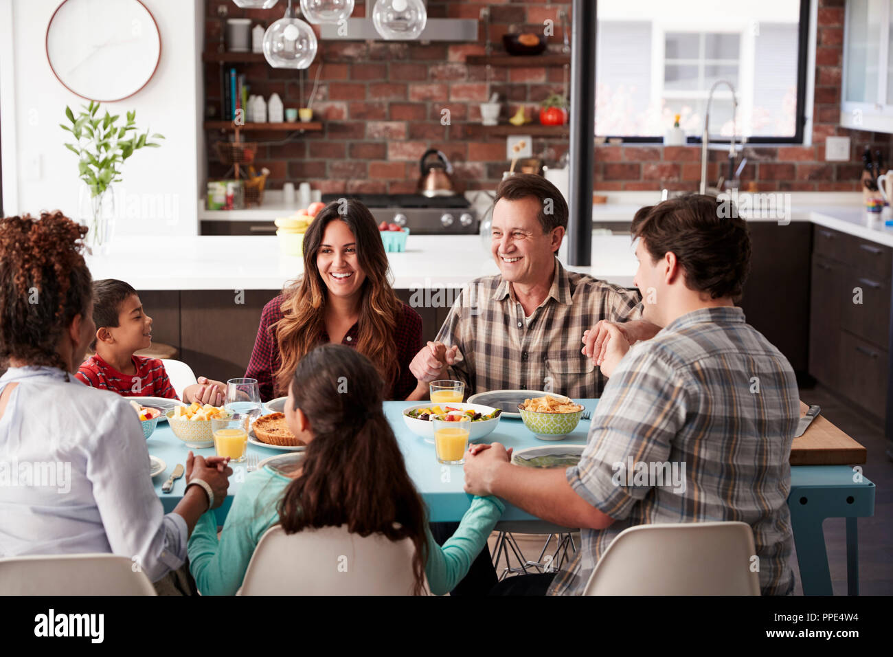 Multi Generation Family priant Avant repas autour de la table à la maison Banque D'Images