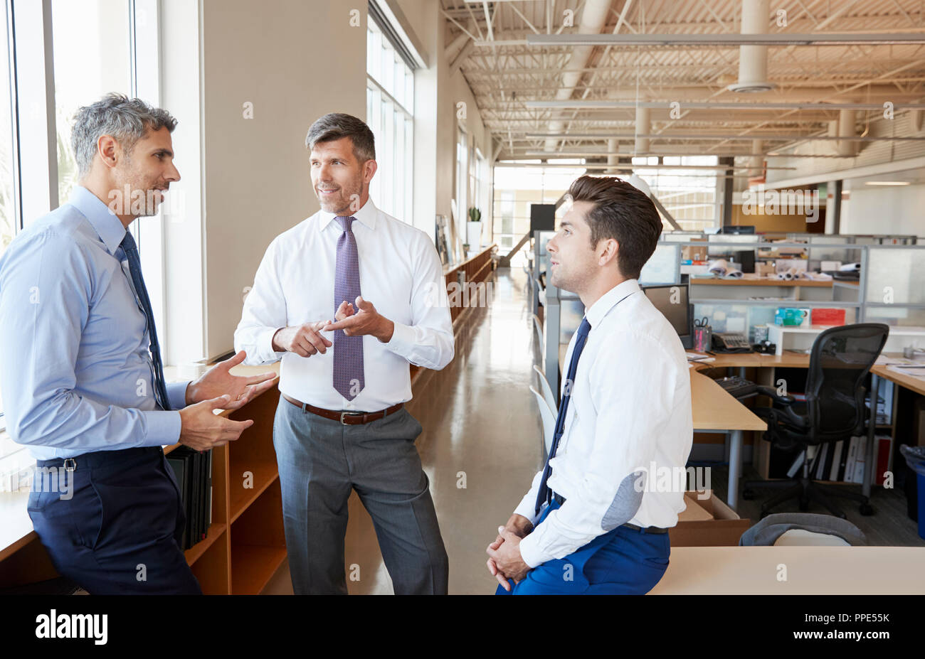 Trois collègues masculins en discussion au travail Banque D'Images