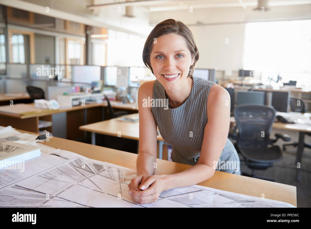Young leaning on desk smiling to camera Banque D'Images