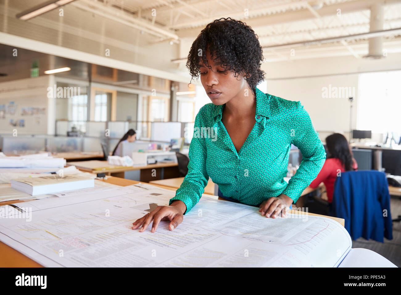 Black female architect l'étude de plans en open plan office Banque D'Images