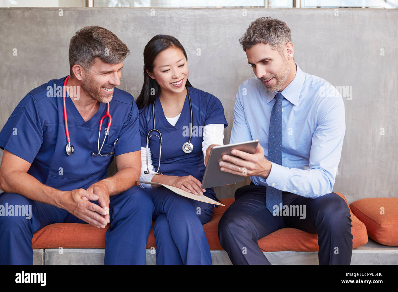 Trois travailleurs de la santé s'asseoir à l'aide de tablet computer together Banque D'Images