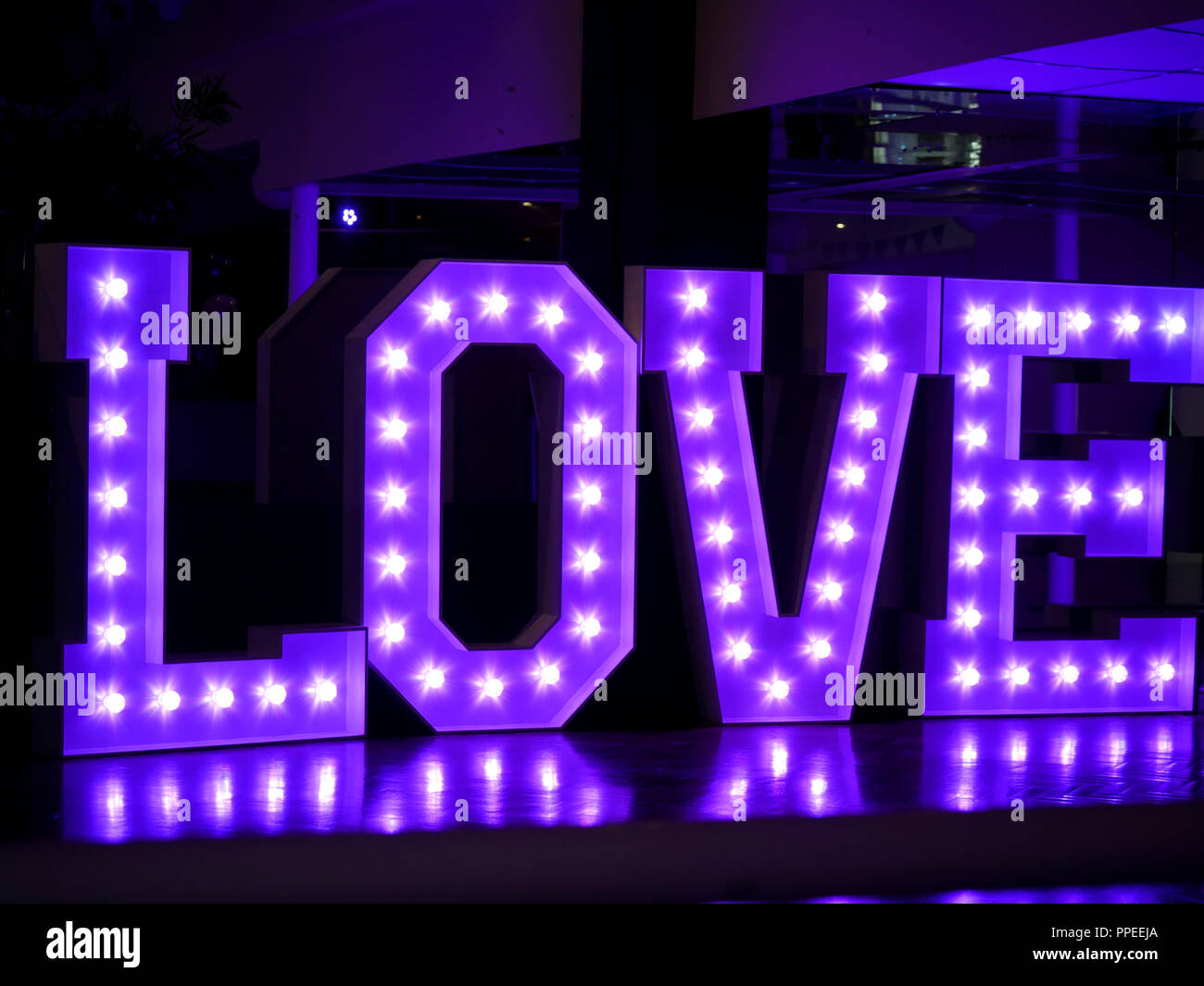 Grand Amour dans des lettres en violet avec des lumières blanches à l'intérieur Banque D'Images
