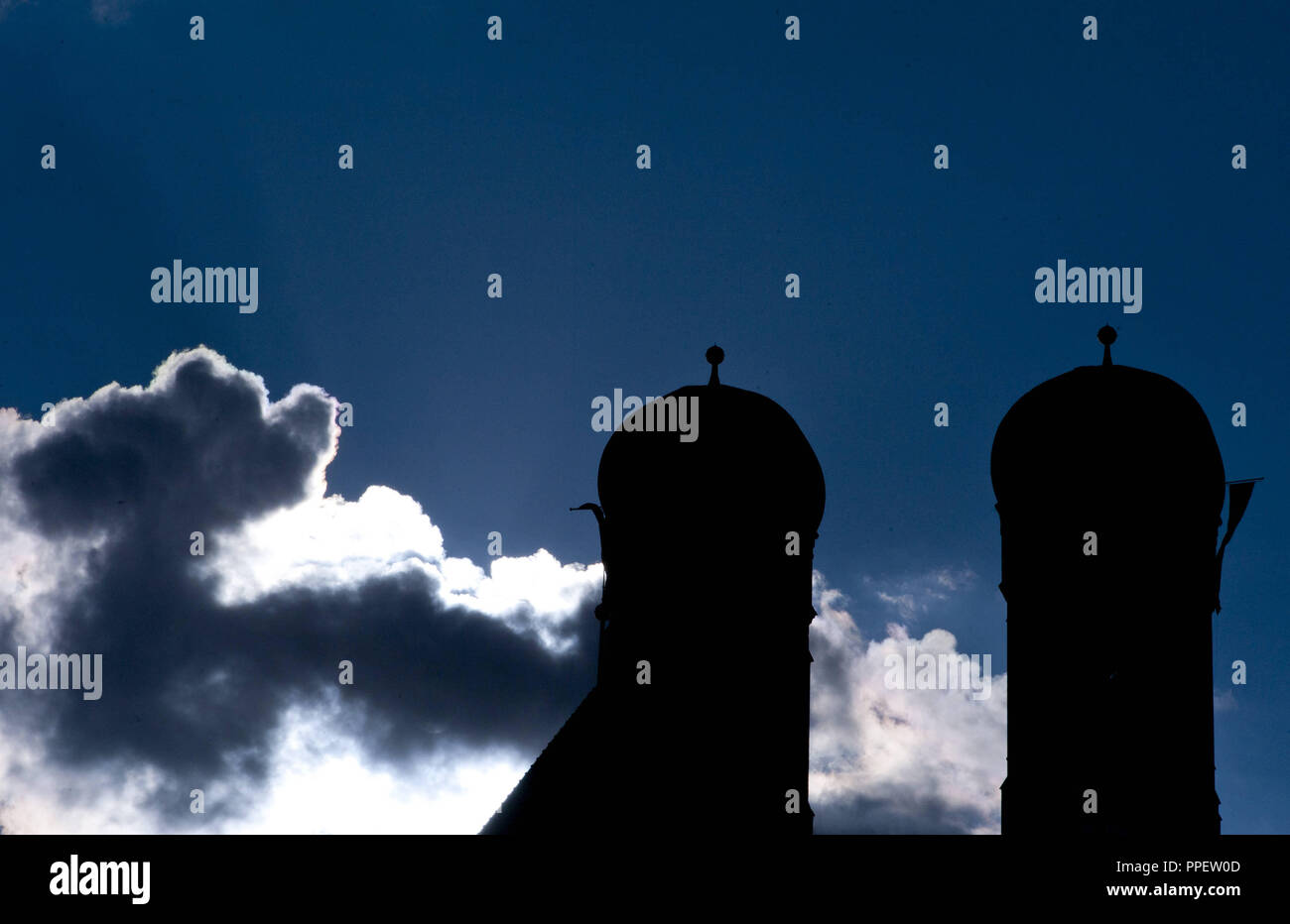 La silhouette de deux tours de la Frauenkirche de Munich, en face d'un ciel nuageux et soleil. Banque D'Images