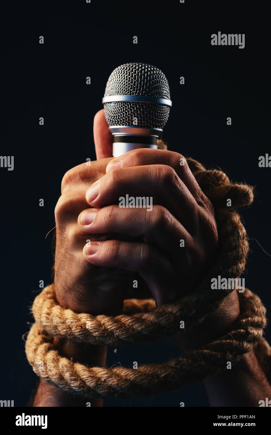 La liberté de parole, conceptual image avec personne mâle tenant un microphone avec les mains liées dans les cordages, faible image clé Banque D'Images