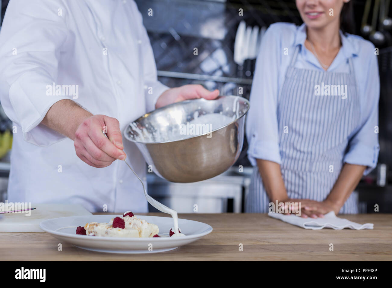 Ajouter un peu de crème chef confiant à un dessert Banque D'Images